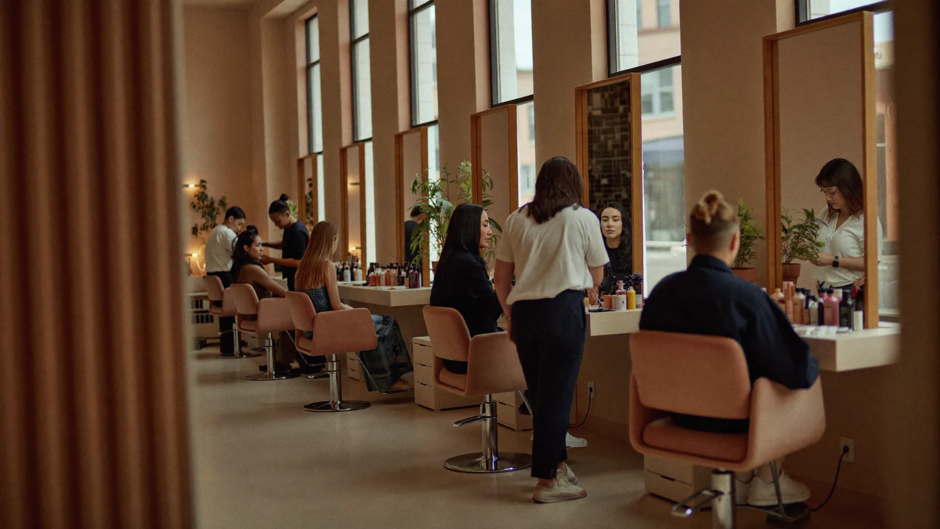 Geräumiger moderner Salon mit einer Reihe von Spiegelplätzen und Friseuren mit Kunden